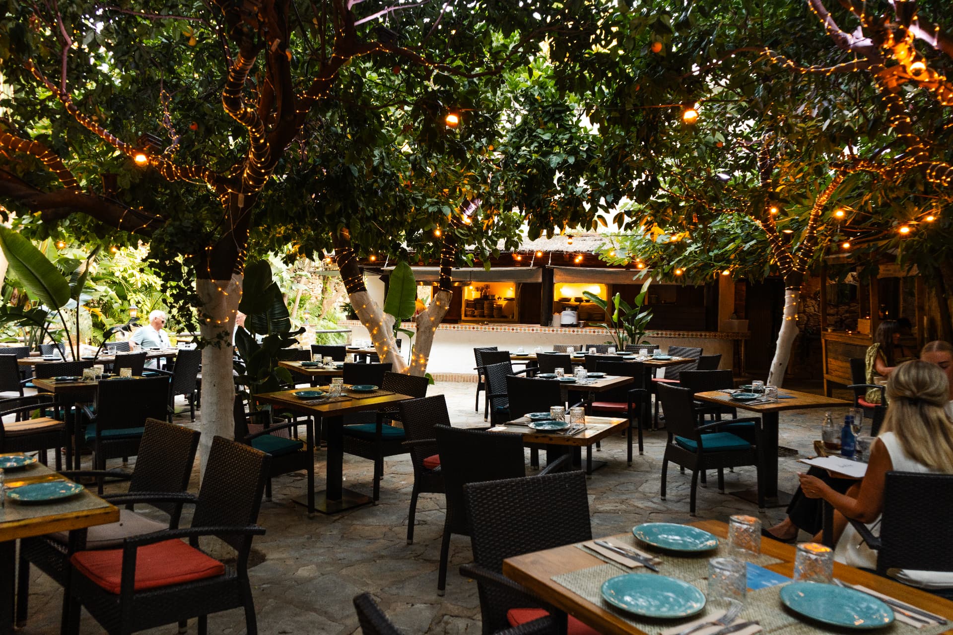 Le Patio at dusk, tables set beneath trees strung with warm lights